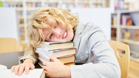 Schüler legt Kopf auf Büchern ab Schüler legt Kopf auf Büchern ab
