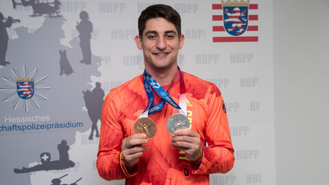 Eduard Trippel hält seine Medaillen der Olympischen Spiele in Tokia 2021 in den Händen und lächelt in die Kamera