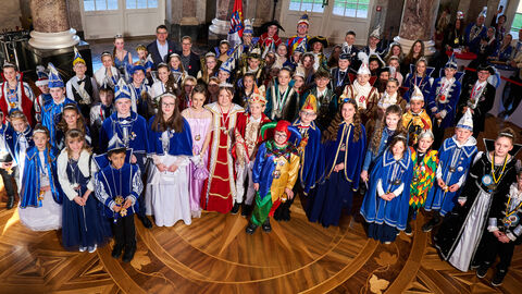 Boris Rhein und Tanja Raab-Rhein stehen mit 30 verkleideten Kinderprinzenpaare im Schloss Biebrich. 