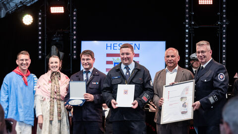 Drei Personen halten eine Auszeichnung in der Hand