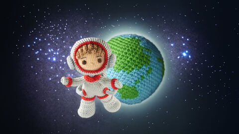 Ein gehäkelte Astronautenfigur vor einer gehäkelten Erde fliegt im Weltraum