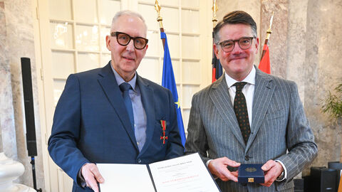 Zwei Männer stehen nebeneinander und halten eine Urkunde hoch.