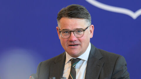 Ministerpräsident Boris Rhein sitzt an einem Tisch im Rahmen einer Pressekonferenz und spricht.