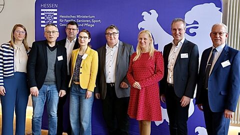 9 Männer und Frauen stehen nebeneinander.