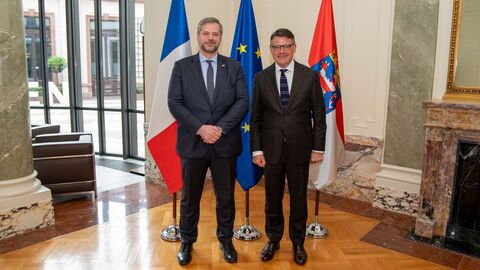 Ministerpräsident Rhein und der französische Generalkonsul Nicolas Bergeret stehe in einem Raum vor den Flaggen von Frankreich, Hessen und der EU.